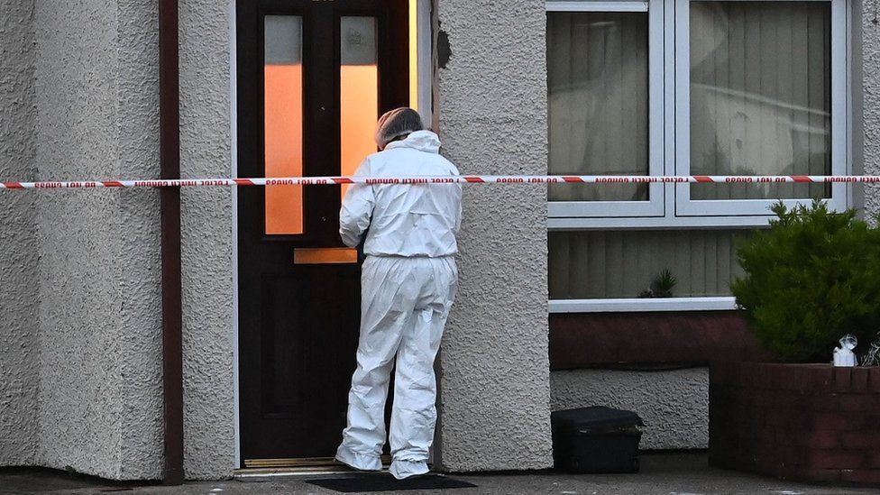 A forensic officer stands at the front door of the flat in which Brian Coulter was found dead