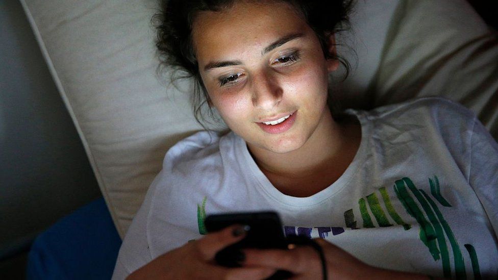A teenager looks at her phone