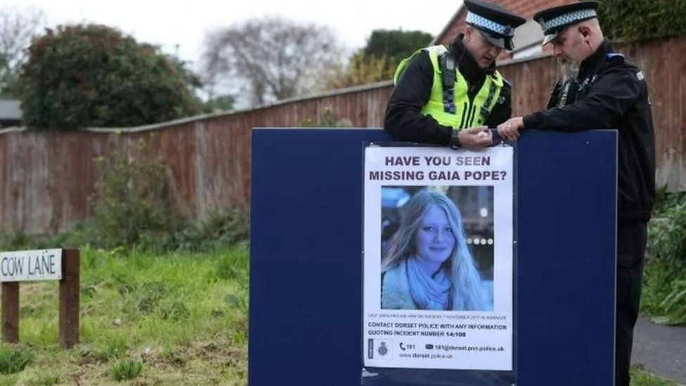 two police officers put up a missing poster for Gaia Pope