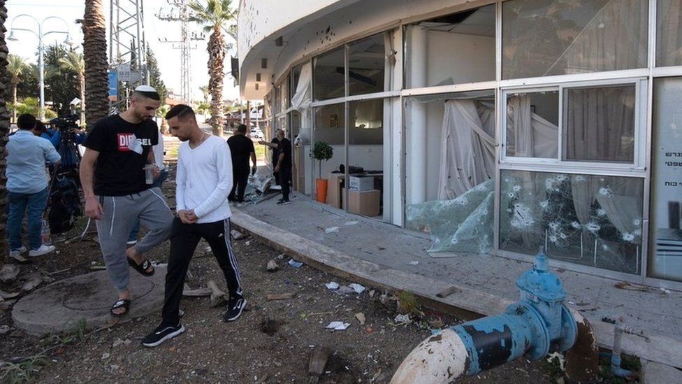 Израильтяне осматривают здание в северном городе Шломи, пострадавшее от ракетного обстрела из Ливана (6 апреля 2023 г.)