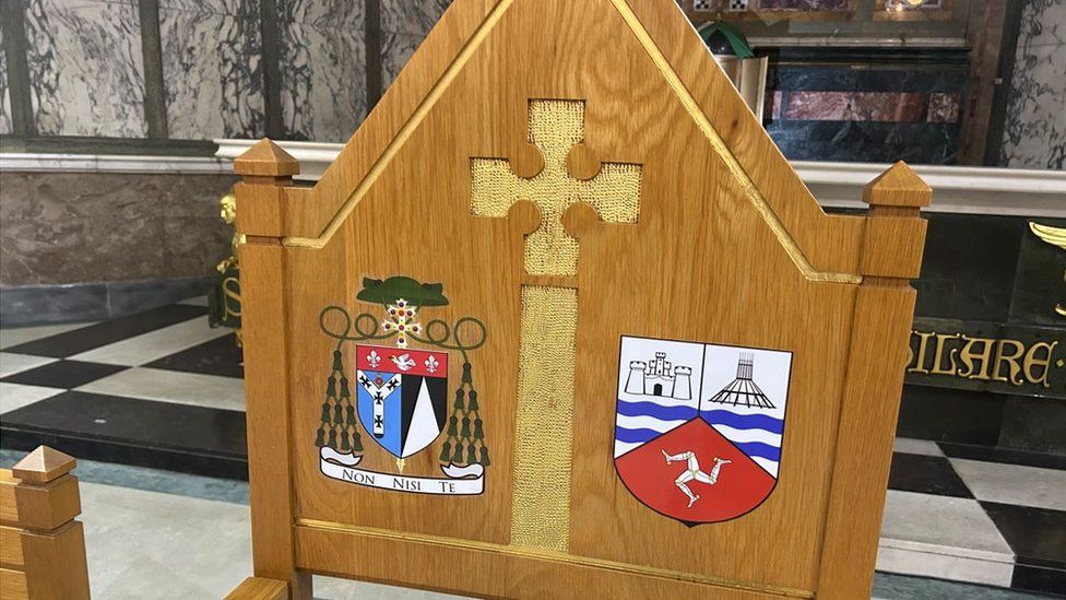 The specially designed coat of arms blending Archdiocesan and Manx symbols