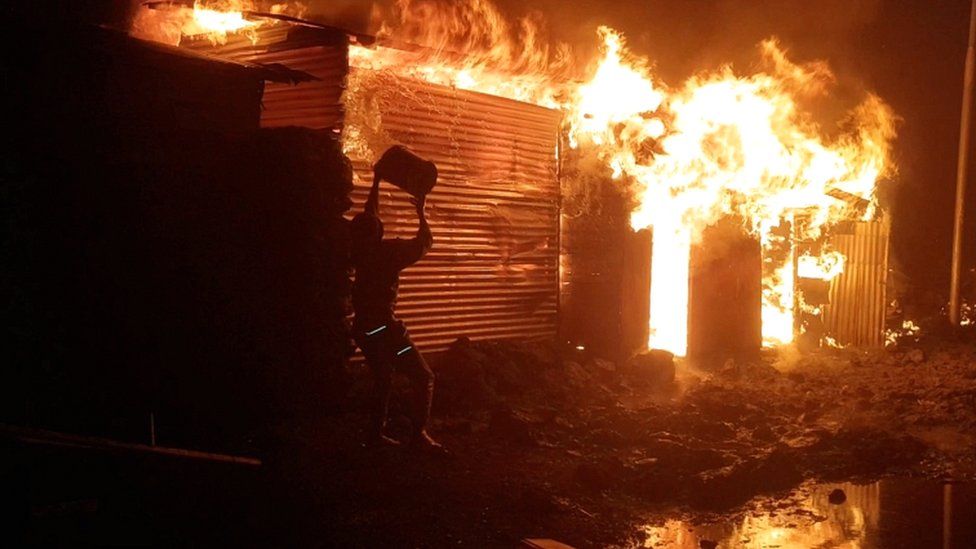 A person attempts to extinguish fire on a building after the volcanic eruption of Mount Nyiragongo, which occurred late on 22 May 2021, in Goma, Democratic Republic of Congo