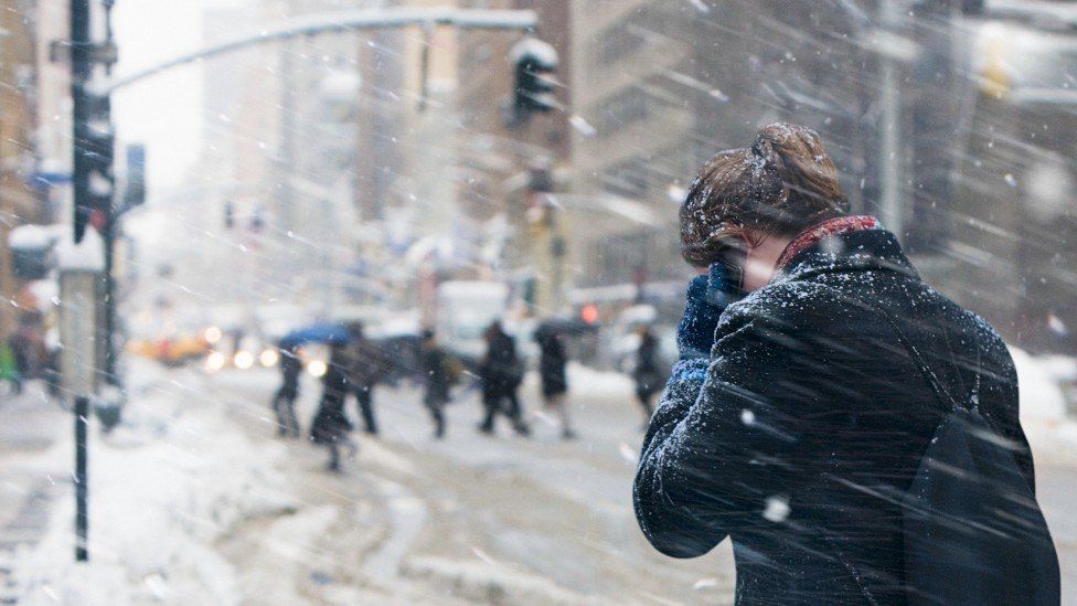 A young woman on her phone in a snow storm in the US