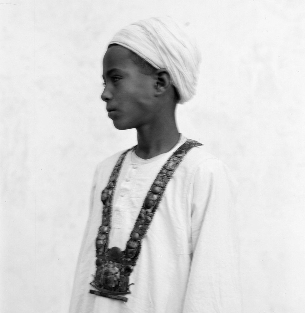 Blurred photograph of boy wearing gold necklace artefact