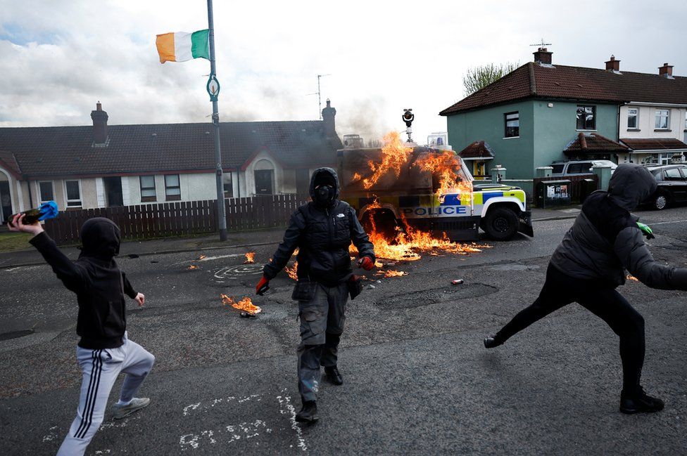 Young hooded men throw a petrol bomb at a police vehicle in Londonderry