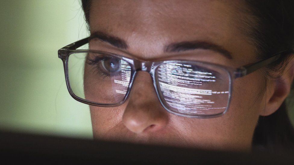 Computer programmer wearing glasses looking at codes.