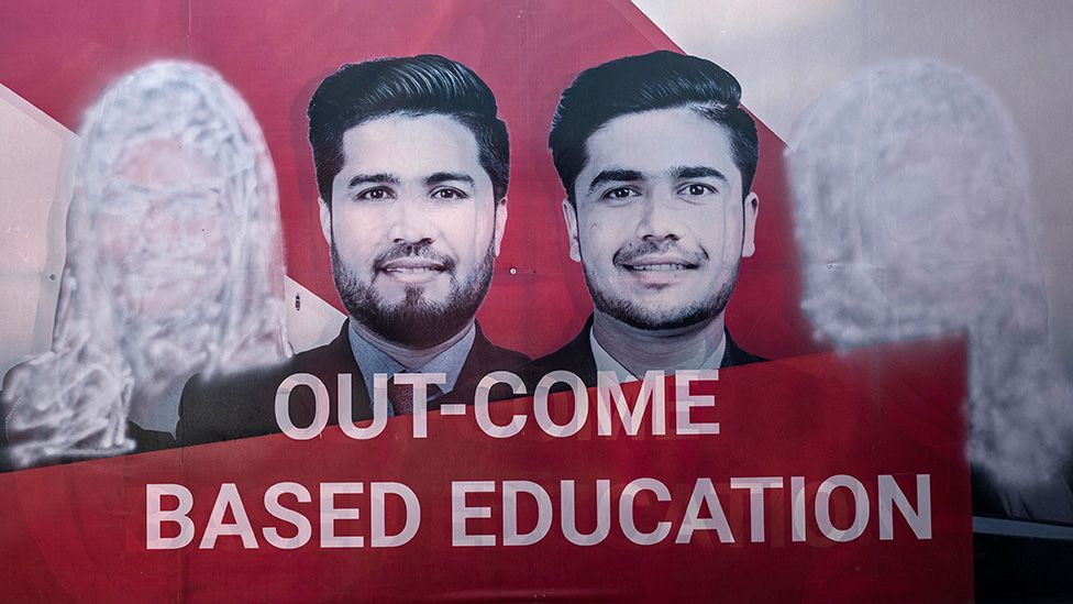 A banner seen with images of women defaced using spray paint after the universities were reopened in Kabul