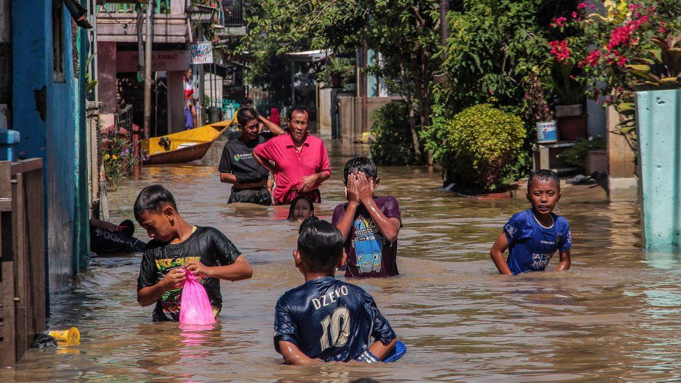 boys wade through flooded street