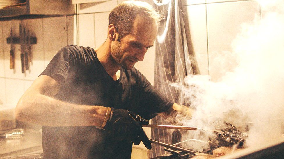 Man working over a barbecue in a fast food restaurant