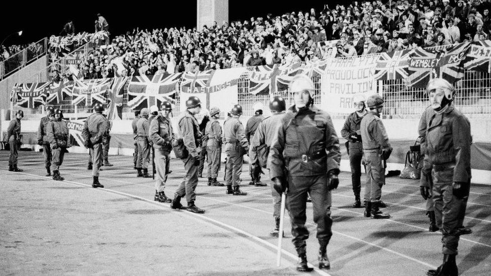 Riot police watch England fans as the national side play Luxembourg in 1983