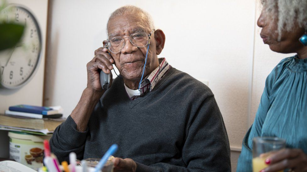 An elderly man talking on the telephone