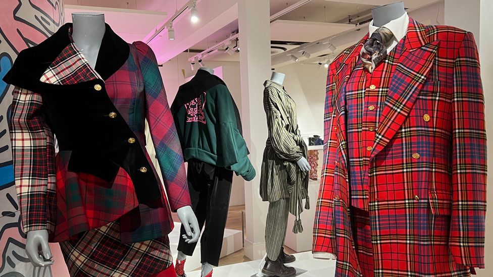 Two mannequins, one wearing multi-coloured tartan clothing and the other wearing a man's red tartan suit, both Vivienne Westwood, Northampton Gallery
