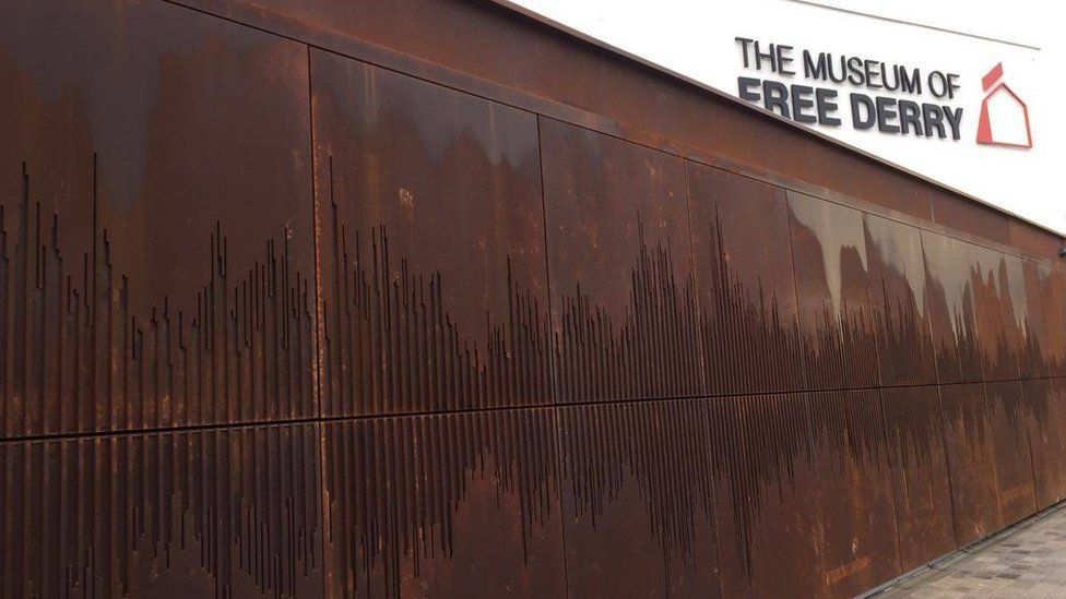The outside wall shows a sound wave of 'We Shall Overcome'