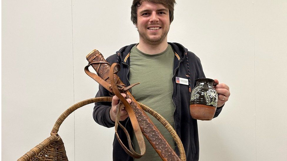 EACH staff member holding some of the props including a black jug with white paintings on it and a sword sheath and wicker basket