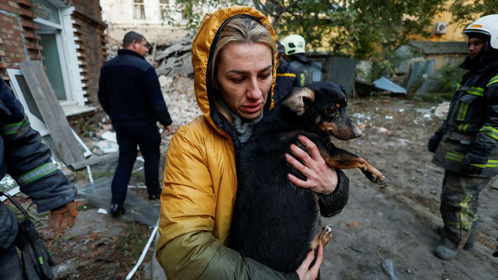 A local woman carries her dog at the site of a residential building heavily damaged by a Russian missile strike, amid Russia's attack on Ukraine, in Mykolaiv, Ukraine October 18, 2022