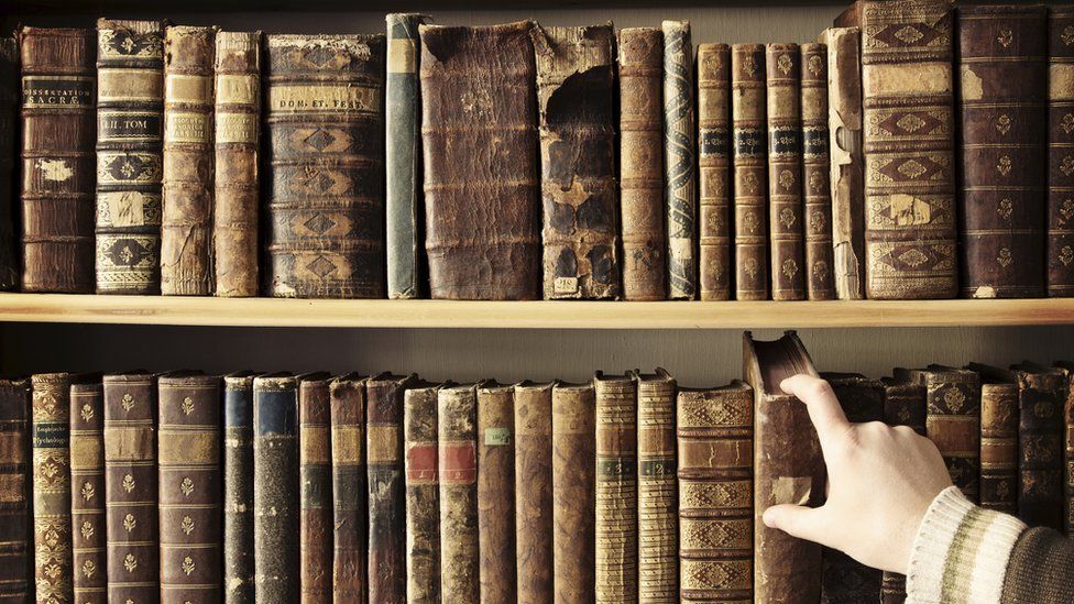 Hand reaches to shelf of second-hand books