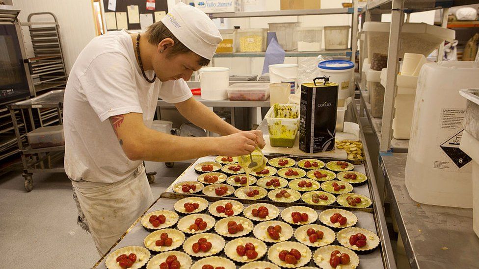 A worker makes quiches