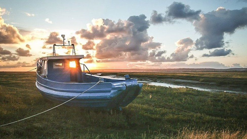 A fishing boat tied up on the grass near Crofty in Swansea