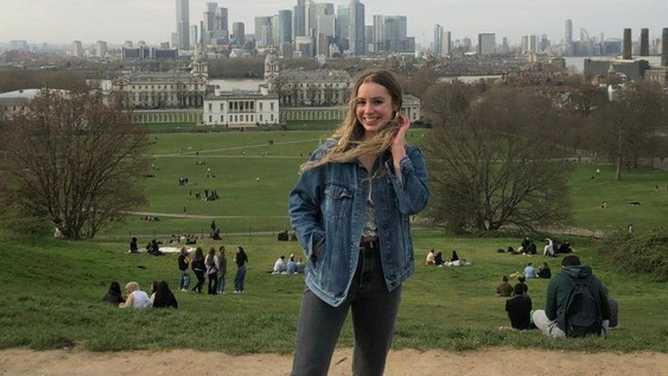 Ella Watson stands on a hill with the City of London behind her