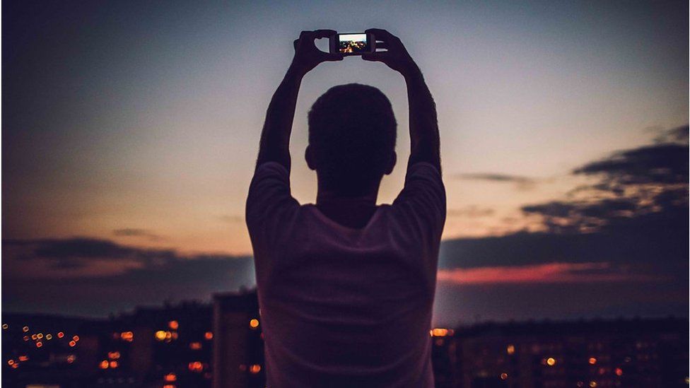 stock image of someone taking a photograph of a city skyline at dusk