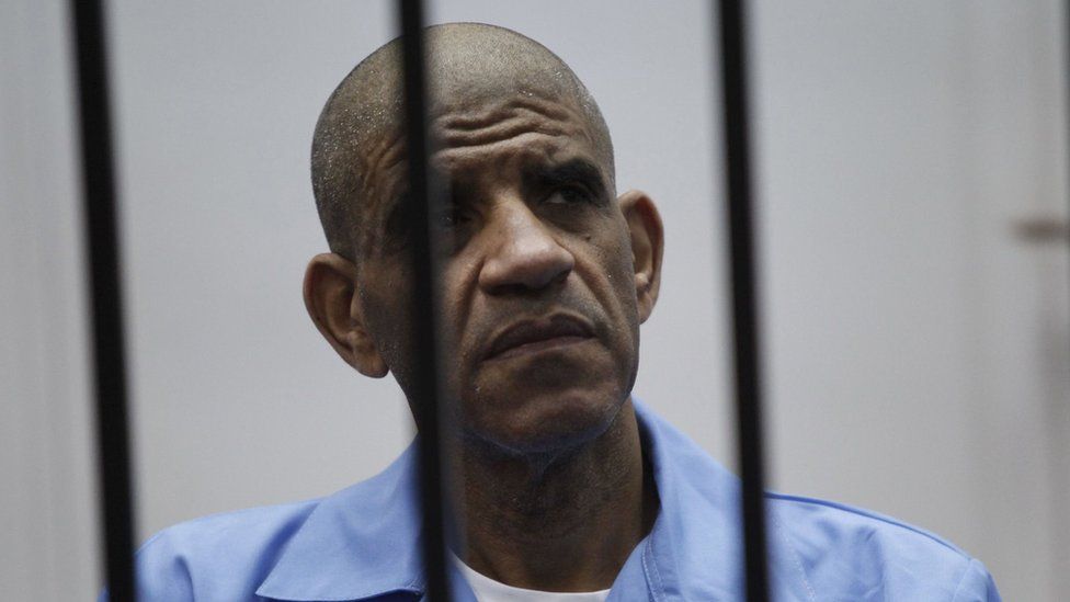 Former spy chief Abdullah al-Senussi dressed in prison blue behind the bars of the accused cell during their trial at court of appeals in the Libyan capital, Tripoli