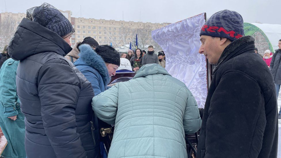 Image of people gathered around a coffin at Denys Sosnenko's funeral