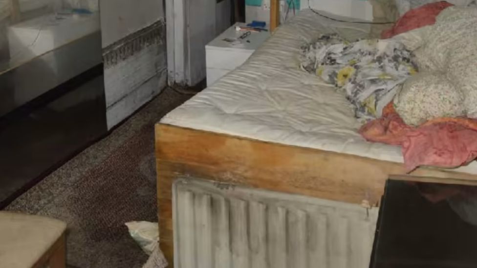 Police photos showing a heavily-stained bed inside the shipping container