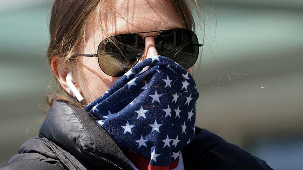 A woman wearing a stars and stripes bandana for a face mask
