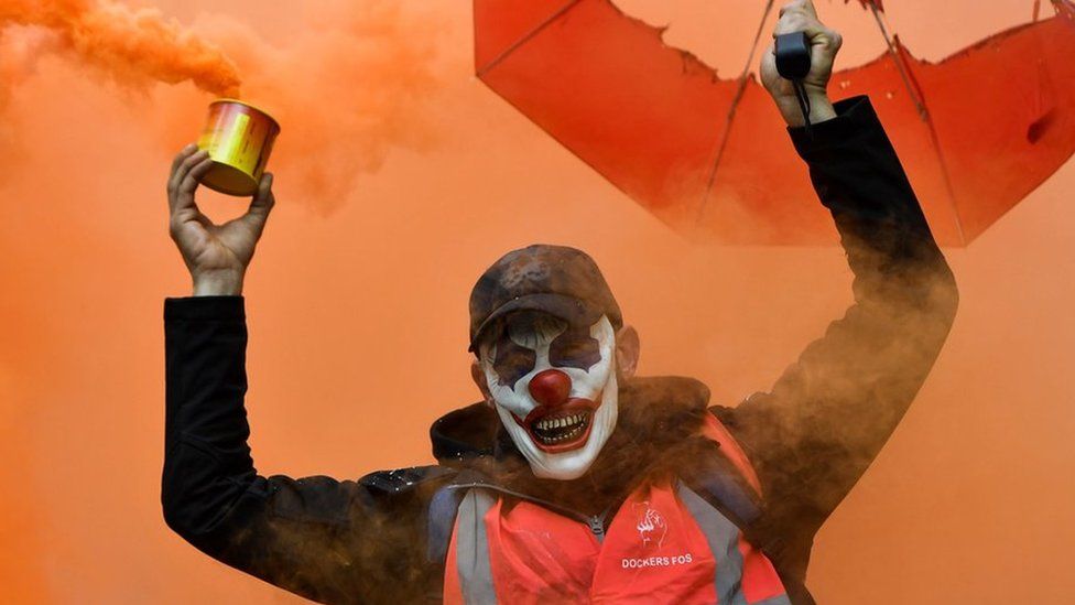 A man wearing a clown mask and waving a smoke bomb takes part in a demonstration to protest against the pension overhauls, in Marseille, southern France, on 5 December, 2019.