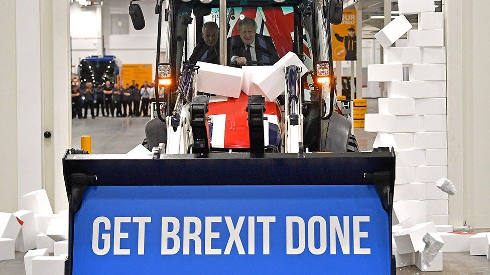 Boris Johnson driving a JCB knocks down Brexit sign