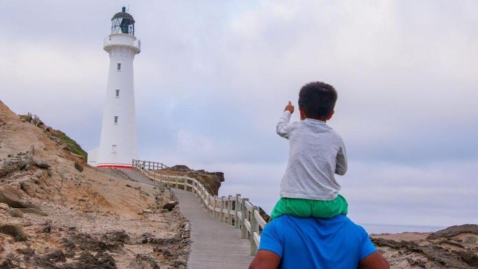 Menino em frente a farol
