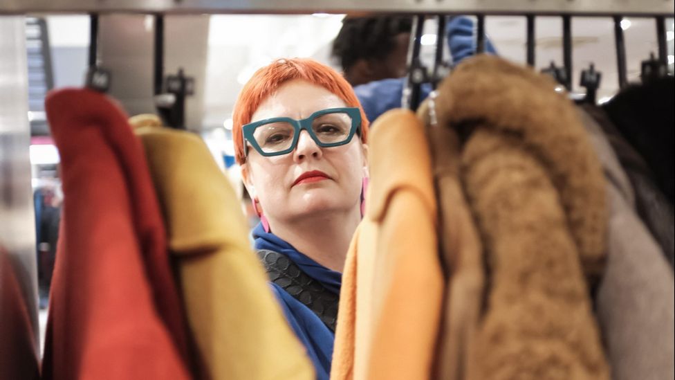 Women looks through rack of clothes in Charity Super.Mkt