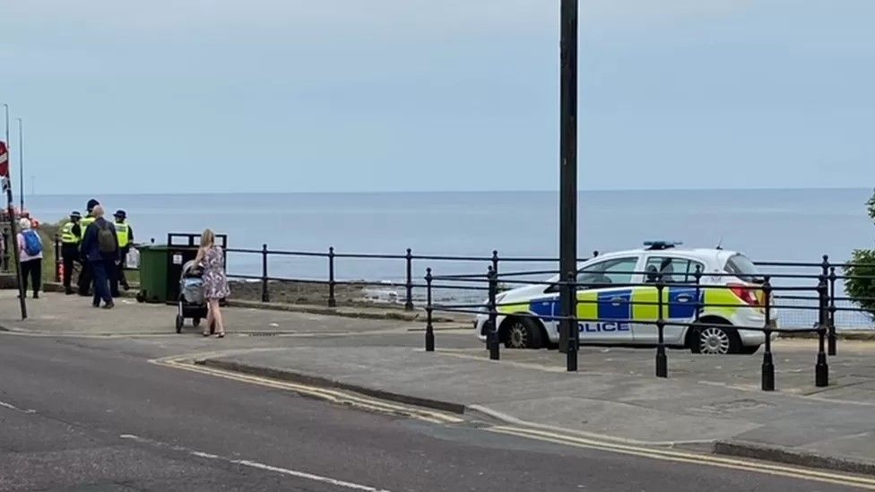 A police car on a road overlooking the beach