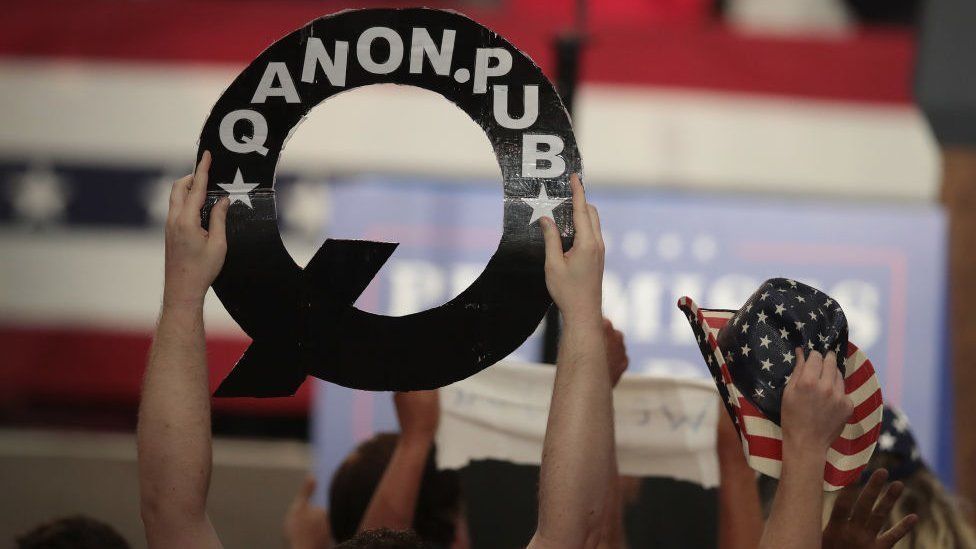 QAnon supporter holds up poster at Trump rally