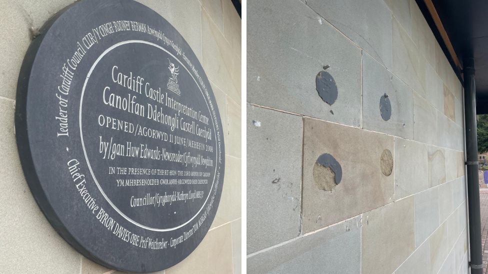 Round slate plaque on right, which says the Cardiff Council Interpretation Centre was opened by Huw Edwards, and the empty wall on the right, with markings where the plaque has been removed