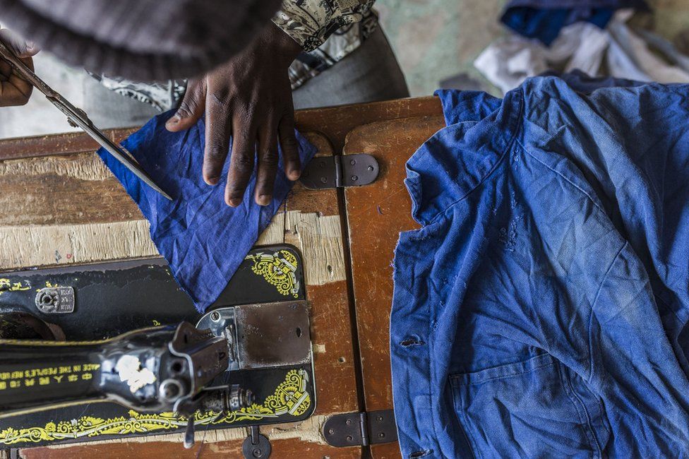 A tailor customises the salvaged clothing.