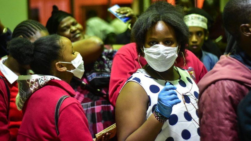Travellers wearing face masks as protective measure wait to get their temperature checked at the border post with Kenya in Namanga