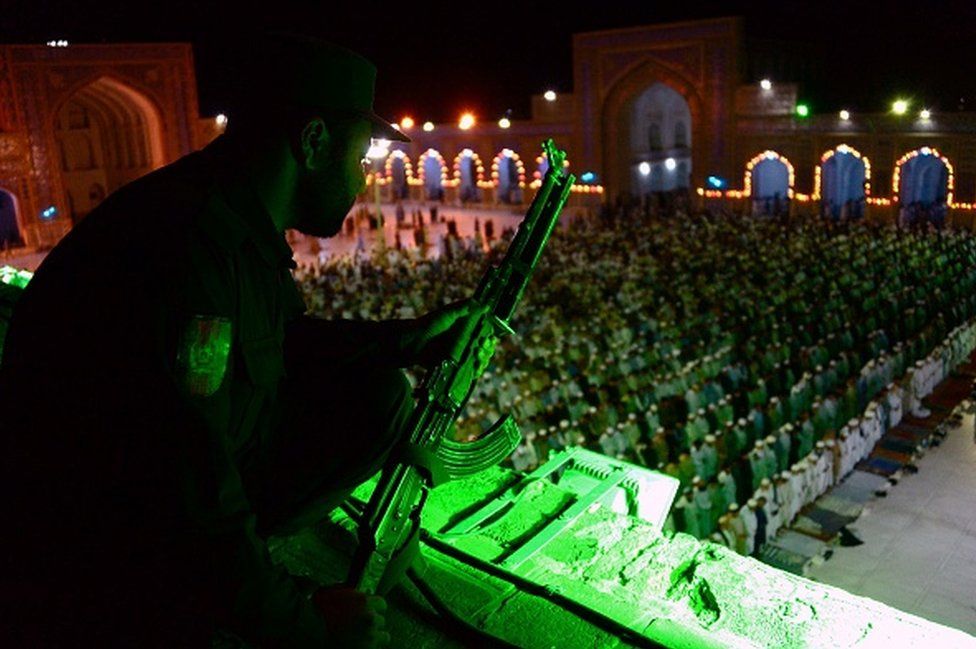 An Afghan policeman watches over worshippers during Ramadan