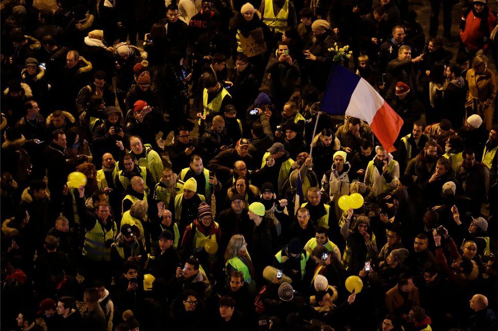 Protestors wearing "Yellow vests" wave the French national flag at the Champs-Elysees as the French capital Paris, 31 December