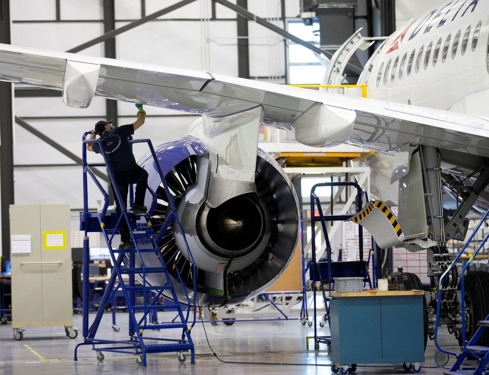 An aerospace employee works on a wing on an Airbus A220