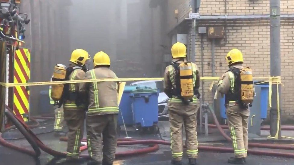 firefighters tackle the blaze from the lane behind