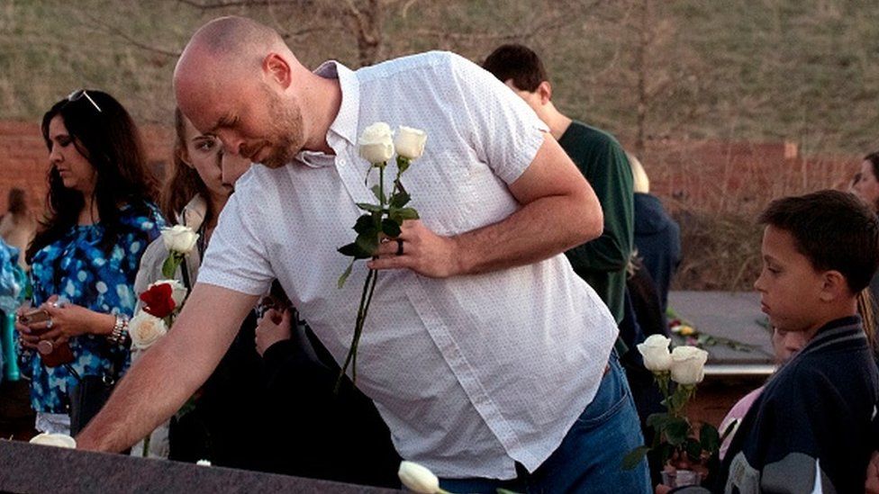 Survivor Will Beck places flowers at the Columbine Memorial at Clement Park in Littleton, Colorado