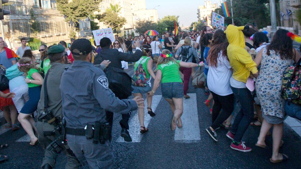Israeli security forces reach for an ultra-Orthodox Jew attacking people with a knife during a Gay Pride parade Thursday, July 30, 2015