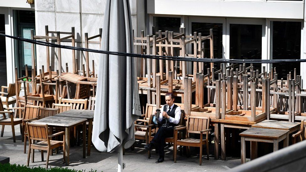 File image showing a man sitting on a chair outside a closed pub in Canary Wharf