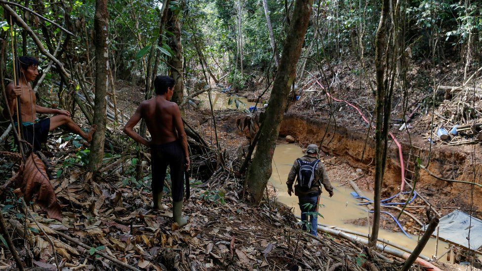 Yanomami indians follow agents of Brazil"s environmental agency in a gold mine during an operation against illegal gold mining on indigenous land on 17 April 2016