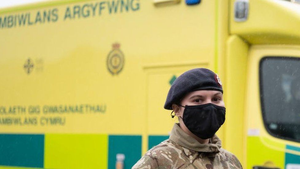 A member of the armed forces in front of a Welsh ambulance
