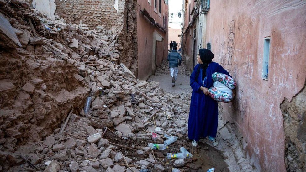 Женщина осматривает разрушенное здание в Марракеше, почти полностью превращенное в руины