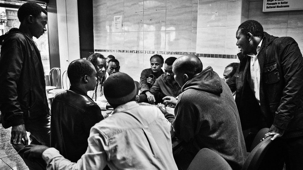 A group of men play domino's in an African café in Newport