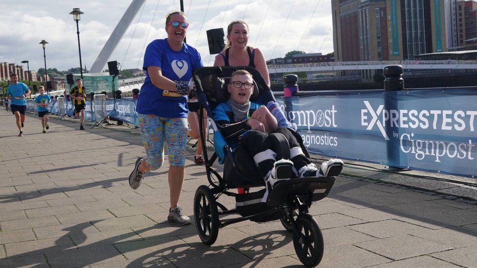 A disabled participant is pushed towards the finishing line in his buggy