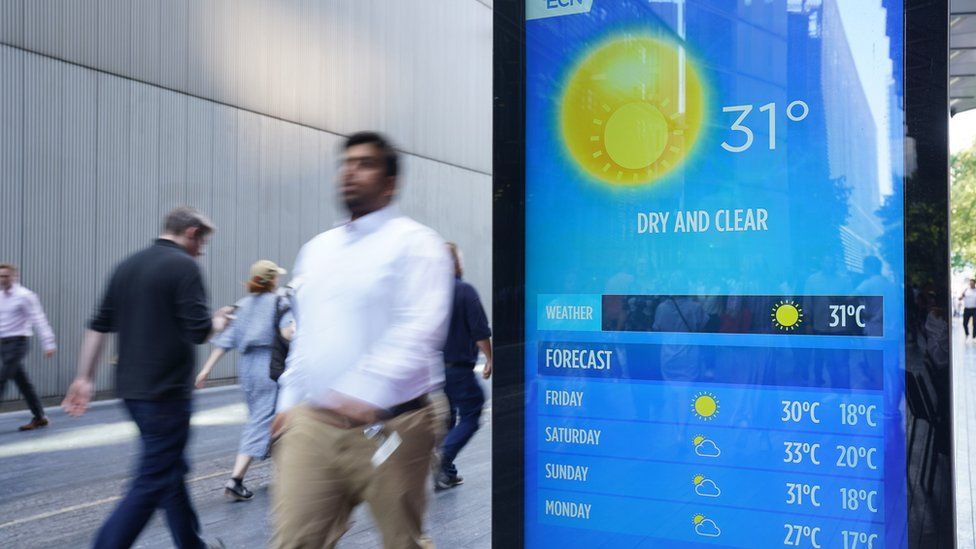 A man walks past a screen with predicted temperatures in London